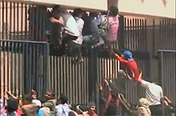 Protestors attempt to scale the gate of the US embassy in Yemen.