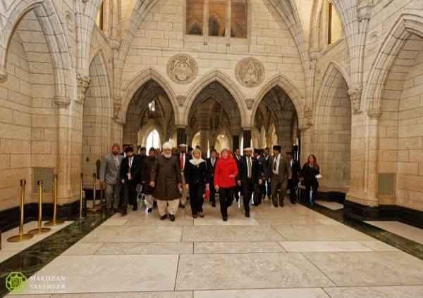 His Holiness walks through the halls of Parliament accompanied by MP Judy Sgro and other guests. © Makhzan-e-Tasaweer